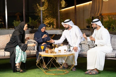 الجلسة الليلة الخارجية في احدى شاليهات الامارات، زينة واضاءة رمضانية، حسن الاستقبال وكرم الضيافة في شهر رمضان المبارك، مجموعة من الأصدقاء العرب الخليجيين الاماراتيين يجلسون في الهواء الطلق، تبادل الاحاديث والاخبار بتعابير السرور والسعادة