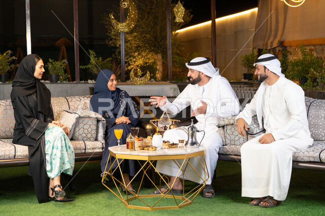 جودة الاستقبال وكرم الضيافة في شهر رمضان المبارك، الجلسة الليلة الخارجية في احدى شاليهات الامارات، زينة واضاءة رمضانية، مجموعة من الأصدقاء العرب الخليجيين الاماراتيين يجلسون في الهواء الطلق، تبادل الاحاديث والاخبار بتعابير السرور والسعادة