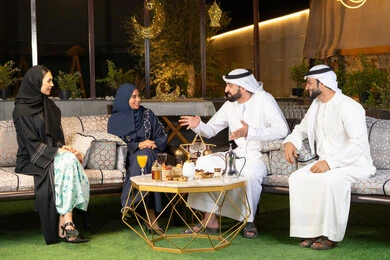 جودة الاستقبال وكرم الضيافة في شهر رمضان المبارك، الجلسة الليلة الخارجية في احدى شاليهات الامارات، زينة واضاءة رمضانية، مجموعة من الأصدقاء العرب الخليجيين الاماراتيين يجلسون في الهواء الطلق، تبادل الاحاديث والاخبار بتعابير السرور والسعادة