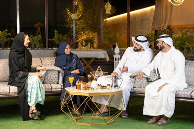 جلسة ليلية خارجية في احدى شاليهات الامارات، زينة واضاءة رمضانية، حسن الاستقبال وكرم الضيافة في شهر رمضان المبارك، مجموعة من الأصدقاء العرب الخليجيين الاماراتيين يجلسون في الهواء الطلق، تبادل الاحاديث والاخبار بتعابير السرور والسعادة