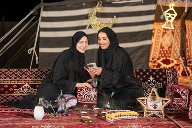 سيدتان اماراتيتان مبتستمتان تستمتعان بالنظر الي الهاتف، حسن الضيافة والاستقبال عند العرب، استخدام التقنيات الحديثه، امرأة عربية خليجية سعودية ترتدي العباءة السوداء تقوم بمشاركه صديقتها في التسوق عبر الانترنت، ايماءه الضحك والسرور سيدتان اماراتيتان مبتستمتان تستمتعان بالنظر الي الهاتف، حسن الضيافة والاستقبال عند العرب، استخدام التقنيات الحديثه، امرأة عربية خليجية سعودية ترتدي العباءة السوداء تقوم بمشاركه صديقتها في التسوق عبر الانترنت، ايماءه الضحك والسرور