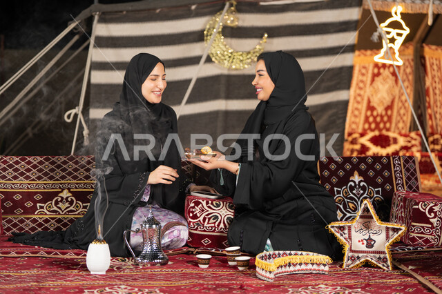 وجبة افطار ذات قيمة غذائية عالية, كرات العجين المقلية الصغيرة, مأكولات على المائدة في شهر رمضان, حسن الاستقبال وكرم الضيافه، سيده امارتيه تقوم بتقدم المقبلات لصديقتها، امراءه سعوديه تحمل بيدها طبق مليئ بالمأكولات