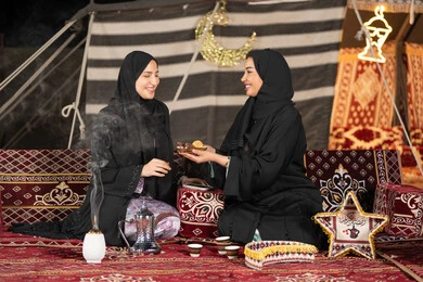 وجبة افطار ذات قيمة غذائية عالية, كرات العجين المقلية الصغيرة, مأكولات على المائدة في شهر رمضان, حسن الاستقبال وكرم الضيافه، سيده امارتيه تقوم بتقدم المقبلات لصديقتها، امراءه سعوديه تحمل بيدها طبق مليئ بالمأكولات