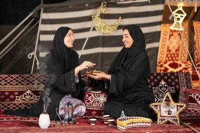 وجبة افطار ذات قيمة غذائية عالية, كرات العجين المقلية الصغيرة, مأكولات على المائدة في شهر رمضان, حسن الاستقبال وكرم الضيافه، سيده امارتيه تقوم بتقدم المقبلات لصديقتها، امراءه سعوديه تحمل بيدها طبق مليئ بالمأكولات