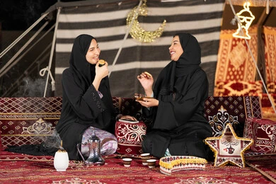 وجبة افطار ذات قيمة غذائية عالية, كرات العجين المقلية الصغيرة, مأكولات على المائدة في شهر رمضان, حسن الاستقبال وكرم الضيافه، سيده امارتيه تقوم بتقدم المقبلات لصديقتها، امراءه سعوديه تحمل بيدها طبق مليئ بالمأكولات