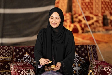 تناول المقبلات اثناء الافطار، امرأه عربيه خليجيه سعوديه مبتسمه تحتفل بقدوم شهر رمضان المبارك, صوره مقربه لسيده اماراتيه ترتدي العباءه والحجاب الاسود تمسك بفانوس معدني ملون, خيمه مليئه بزينه وديكورات رمضانيه, التخييم الليلي الهادئ
