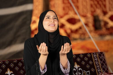 الاجتهاد في الطاعات والأدعية، الخشوع والتضرع والطلب من الله، العبادة والتقرب الى الله، إمرأة عربية خليجية سعودية ترتدي الحجاب والعباءة التقليدية ترفع يديها وتنظر الي السماء، سيده اماراتيه تتذلل في طلب الدعاء