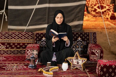 الطمأنينه والخشوع بتلاوه القرآن, إمرأة عربية سعودية خليجية ترتدي الحجاب والعباءة السوداء تحمل بيدها المصحف الشريف, الإكثاروالإجتهاد في العباده, التقرب الى الله في شهر رمضان، سيده اماراتيه تتدبر وتقرأ آيات القرآن الكريم