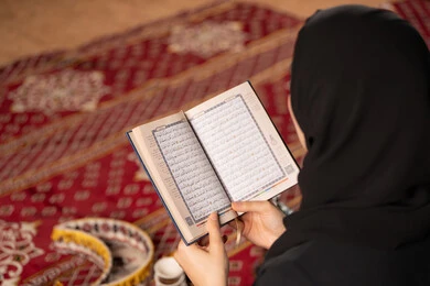 مشاعر الطمأنينه والخشوع بتلاوه القرآن, صوره مقربه ليدين إمرأة عربية سعودية خليجية ترتدي الحجاب والعباءة السوداء تحمل بيدها المصحف الشريف, الإكثاروالإجتهاد في العباده, التقرب الى الله في شهر رمضان، سيده اماراتيه تتدبر وتقرأ آيات القرآن الكريم