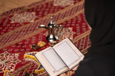 مشاعر الطمأنينه والخشوع بتلاوه القرآن, صوره مقربه ليدين إمرأة عربية سعودية خليجية ترتدي الحجاب والعباءة السوداء تحمل بيدها المصحف الشريف, الإكثاروالإجتهاد في العباده, التقرب الى الله في شهر رمضان، سيده اماراتيه تتدبر وتقرأ آيات القرآن الكريم