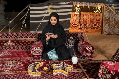 Gestures of pleasure and happiness, chatting with family and friends, using modern advanced technology and techniques, a veiled Saudi Arabian Gulf woman looking at the phone, an Emirati woman responding to text messages, using modern technologies and devices