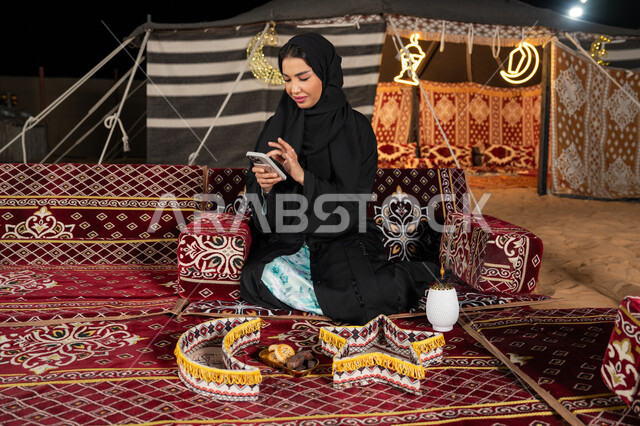 إيماءات السرور والسعادة، الدردشه مع الأهل والأصدقاء، استخدام التكنولوجيا والتقنيات الحديثة المتطورة، امرأة عربية سعودية خليجية محجبة تنظرالي الهاتف، سيده اماراتيه تقوم بالرد على الرسائل النصيه، استخدام التقنيات والاجهزه الحديثه