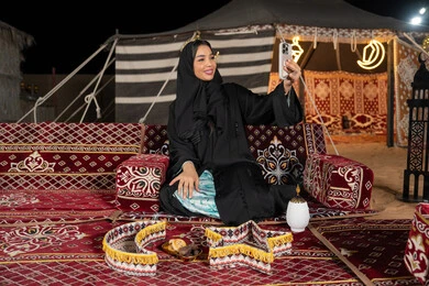 امرأة عربية سعودية خليجية تقوم بإلتقاط صورة سيلفي تذكارية من خلال الجهاز المحمول, توثيق اللحظات السعيدة، إستخدام الأجهزة التقنية الحديثة، سيده اماراتيه تحمل الهاتف المحمول تأخذ صوره تذكاريه، التقدم والتطورالتقني