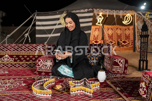 إيماءات السرور والسعادة، الدردشه مع الأهل والأصدقاء، استخدام التكنولوجيا والتقنيات الحديثة المتطورة، امرأة عربية سعودية خليجية محجبة تنظرالي الهاتف، سيده اماراتيه تقوم بالرد على الرسائل النصيه، استخدام التقنيات والاجهزه الحديثه