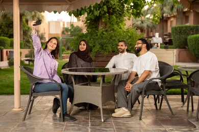 توثيق اللحظات التذكارية باستخدام الجوال ، نزهة فى الهواء الطلق ، بناء علاقات اجتماعية ناجحة وتبادل أطراف الحديث بين العائلات والزملاء، الاستمتاع بعطلة نهاية الأسبوع برفقة الأصدقاء في المطاعم والكافيهات،مجموعة اصدقاء عرب خليجيين سعوديين يقضون الاوقات الممتعة في الأجواء الصيفية اللطيفة