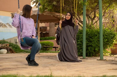 بناء علاقات اجتماعية ناجحة  ،تبادل أطراف الحديث بين العائلات والزملاء، الاستمتاع بعطلة نهاية الأسبوع برفقة الأصدقاء في المطاعم والكافيهات، صديقتان  عربيتان خليجيتان سعوديتان تجلسان على المرجيحة باحدي الحدائق الترفهيه بالسعودية ،يتبادلان الاحاديث في الأجواء الصيفية اللطيفة ، نزهة في الهواء الطلق