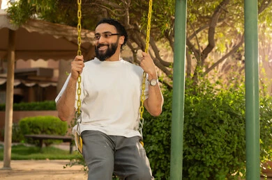 قضاء اوقات سعيده فى الخارج ، بناء علاقات اجتماعية ناجحة  ،الاستمتاع بعطلة نهاية الأسبوع برفقة الأصدقاء في المطاعم والكافيهات، رجل عربي خليجي سعودي  يرتدي الزي الكاجوال يجلس على المرجيحة باحدي الحدائق الترفهيه بالسعودية ،يقوم بتبادل الاحاديث في الأجواء الصيفية اللطيفة ، نزهة في الهواء الطلق