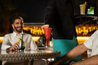 تناول المشروبات الباردة المنعشة  في الهواء الطلق، نادل يرتدي زي اليونيفورم يقوم بتقديم الطلبات ،بناء علاقات اجتماعية ناجحة وتبادل أطراف الحديث بين العائلات والزملاء، الاستمتاع بعطلة نهاية الأسبوع برفقة الأصدقاء في المطاعم والكافيهات، صديقان عربيان خليجيان سعوديان يقضون السهرات المسائية الممتعة في الأجواء الصيفية اللطيفة