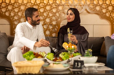 زوجان عربيان خليجيان سعوديان يقضون السهرات المسائية الممتعة في الأجواء الصيفية اللطيفة ، بناء علاقات اجتماعية ناجحة وتبادل أطراف الحديث بين العائلات والزملاء، الاستمتاع بعطلة نهاية الأسبوع برفقة الأصدقاء في المطاعم والكافيهات، تناول المشروبات الباردة المنعشة  في الهواء الطلق