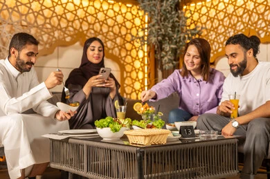 استخدام الهاتف المحمول ، تبادل أطراف الحديث بين العائلات والزملاء، الاستمتاع بعطلة نهاية الأسبوع برفقة الأصدقاء في المطاعم والكافيهات،مجموعة اصدقاء عرب خليجيين سعوديين يقضون السهرات المسائية الممتعة في الأجواء الصيفية اللطيفة ، تناول المشروبات الباردة المنعشة  في الهواء الطلق