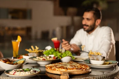 نزهة فى الهواء الطلق ، مأكولات عربيه وصفات شهيه  , صورة من الجانب لرجل عربي خليجي سعودي يرتدي الزي التقليدي يقوم بتناول الطعام , مائده مليئه بأصناف المأكولات و المقبلات الشهية