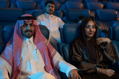 جمهور عربي سعودي خليجي في صالة سينما، صالة عرض رباعية الأبعاد, تقنيات العرض الحديثه, المؤثرات الصوتيه والبصريه والحسيه السينمائيه المتطوره, تجربه سينمائيه خياليه، الاستمتاع بأكل الفشار، تعابير وجه تدل على الفرح والسعاده, نشاط عائلي ترفيهي