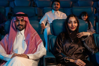 نشاط عائلي ترفيهي، جمهور عربي سعودي خليجي في صالة سينما، صالة عرض رباعية الأبعاد, تقنيات العرض الحديثه, المؤثرات الصوتيه والبصريه والحسيه السينمائيه المتطوره, تجربه سينمائيه خياليه، الاستمتاع بأكل الفشار، تعابير وجه تدل على الفرح والسعاده