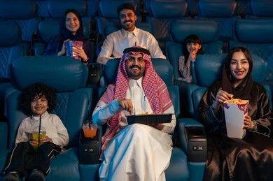 المؤثرات الصوتيه والبصريه والحسيه السينمائيه المتطوره, تجربه سينمائيه خياليه، جمهور عربي سعودي خليجي في صالة سينما، صالة عرض رباعية الأبعاد, تقنيات العرض الحديثه,  الاستمتاع بأكل الفشار، تعابير وجه تدل على الفرح والسعاده, نشاط عائلي ترفيهي