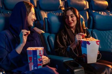 مشاهدة الأفلام والمسرحيات والعروض المتنوعة,الاستمتاع بتناول الفشار ،  شاشات ضوئية كبيرة لزيادة الاستمتاع بالتجربة، القيام بنشاطات ترفيهية ممتعة, صديقتان عربيتان خليجيتان سعوديتان تجلسان في قاعة السينما وتتابعان الفيلم بايماءات السعادة, دور العرض الحديثة في المملكة العربية السعودية