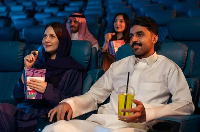 تعابير تدل على الإندماج، جمهور عربي سعودي خليجي في صالة السينما،  الإستمتاع بتناول الفشار والمشروبات الباردة ، أنشطة ترفيهية، قضاء أوقات ممتعة، مشاهدة الأفلام والعروض المسرحية في السينما، سينما ومسرح، خلفية قاعة عرض السينما، صالة العرض