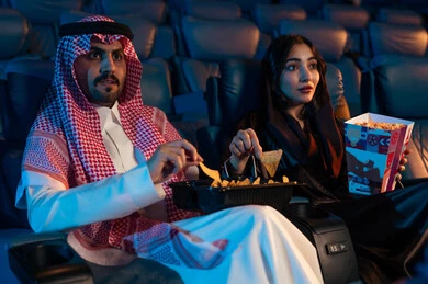 صالات عرض رباعية الأبعاد, أنشطة ترفيهية سعيدة، قضاء أوقات ممتعة، رجل عربي سعودي خليجي بجانب زوجته في صالة السينما، تعابير تدل على الإندماج، الإستمتاع بتناول الفشار والمشروبات الباردة ، مشاهدة الأفلام والعروض المسرحية في السينما، سينما ومسرح، خلفية قاعة عرض السينما