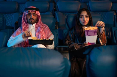 تجربه سينمائيه خياليه، أنشطة ترفيهية سعيدة، قضاء أوقات ممتعة، رجل عربي سعودي خليجي بجانب زوجته في صالة السينما، تعابير تدل على الإندماج، الإستمتاع بتناول الفشار والمشروبات الباردة ، مشاهدة الأفلام والعروض المسرحية في السينما، سينما ومسرح، خلفية قاعة عرض السينما، صالة العرض