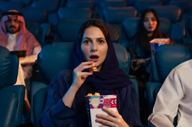 قضاء أوقات ممتعة، تعابير الخوف والذعر ، أنشطة ترفيهية سعيدة،  امراه عربيه سعوديه خليجيه في صالة السينما،  الإستمتاع بتناول الفشار والمشروبات الباردة ، مشاهدة الأفلام والعروض المسرحية في السينما، سينما ومسرح، خلفية قاعة عرض السينما، صالة العرض