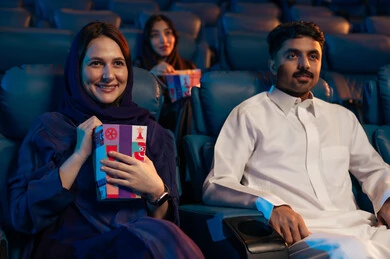 نشاط عائلي ترفيهي  ، جمهور عربي سعودي خليجي في صالة السينما، تعابير تدل على الإندماج، الإستمتاع بتناول الفشار والمشروبات الباردة ،قضاء أوقات ممتعة، مشاهدة الأفلام والعروض المسرحية في السينما، سينما ومسرح، خلفية قاعة عرض السينما، صالة العرض