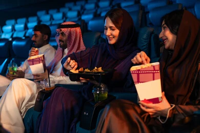 ايماءات السعاده والسرور، جمهور عربي سعودي خليجي في صالة السينما، تعابير تدل على الإندماج، الإستمتاع بتناول الفشار والمشروبات الباردة ، أنشطة ترفيهية، قضاء أوقات ممتعة، مشاهدة الأفلام والعروض المسرحية في السينما، سينما ومسرح، خلفية قاعة عرض السينما، صالة العرض