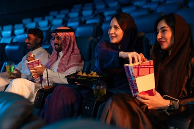 مشاهدة الأفلام والعروض المسرحية في السينما، ايماءات التفاعل والاندماج ، جمهور عربي سعودي خليجي في صالة السينما، الإستمتاع بتناول الفشار والمشروبات الباردة ، أنشطة ترفيهية، قضاء أوقات ممتعة، سينما ومسرح، خلفية قاعة عرض السينما، صالة العرض