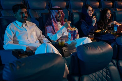 مشاهدة الأفلام والعروض المسرحية في السينما، جمهور عربي سعودي خليجي في صالة السينما، تعابير تدل على الإندماج، الإستمتاع بتناول الفشار والمشروبات الباردة ، أنشطة ترفيهية، قضاء أوقات ممتعة،  سينما ومسرح، خلفية قاعة عرض السينما، صالة العرض