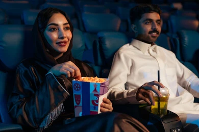 تقنيات عرض حديثة ، أنشطة ترفيهية سعيدة، قضاء أوقات ممتعة، رجل عربي سعودي خليجي في صالة السينما برفقة زوجته ، الإستمتاع بتناول الفشار والمشروبات الباردة ، مشاهدة الأفلام والعروض المسرحية في السينما، سينما ومسرح، خلفية قاعة عرض السينما، صالة العرض