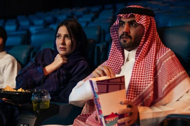الاثارة والتشويق والاندماج ، قضاء أوقات ممتعة، تعابير الخوف والذعر ،رجل عربي سعودي خليجي في صالة السينما برفقة زوجته، الإستمتاع بتناول الفشار والمشروبات الباردة ، مشاهدة الأفلام المرعبه والعروض المسرحية في السينما، سينما ومسرح، خلفية قاعة عرض السينما، صالة العرض
