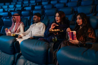 Watching horror movies and theatrical performances in the cinema, expressions of fear and terror, excitement and suspense and immersion, spending enjoyable times, an Arab Saudi Gulf audience in the cinema hall, enjoying popcorn and cold drinks, cinema and theater, background of the cinema screening room, the screening hall.
