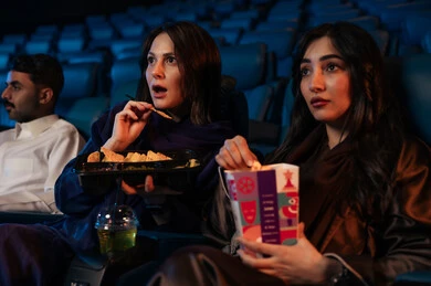 مشاهدة الأفلام المرعبه والعروض المسرحية في السينما، تعابير الخوف والذعر ،الاثارة والتشويق والاندماج ، قضاء أوقات ممتعة، صديقتان عربيتان سعوديتان خليجيتان في صالة السينما ، الإستمتاع بتناول الفشار والمشروبات الباردة ، سينما ومسرح، خلفية قاعة عرض السينما، صالة العرض
