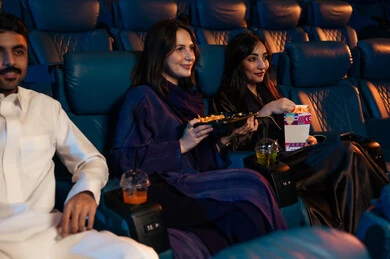 Engaging in enjoyable recreational activities, an Arab Gulf Saudi audience sitting in the cinema hall watching the film with gestures of happiness, watching movies, plays, and various shows, large screens to enhance the enjoyment of the experience, modern theaters in the Kingdom of Saudi Arabia.