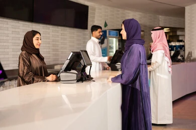 امراه عربية سعودية خليجية ترتدي العباءه والحجاب تقوم بحجز تذكرة لمشاهدة فيلم في صالة السينما، مشاهدة الأفلام والعروض المسرحية  ، أنشطه ترفيهيه متميزة