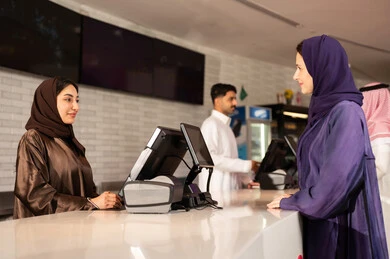 أنشطه ترفيهيه متميزة ، امراه عربية سعودية خليجية ترتدي العباءه والحجاب تقوم بحجز تذكرة لمشاهدة فيلم في صالة السينما، مشاهدة الأفلام والعروض المسرحية