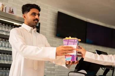 تجربة سينمائية خيالية ،رجل عربي سعودي خليجي مبتسم يرتدي الزي التقليدي والشماغ يقوم بشراء الفشار فى صاله حجز التذاكر لمشاهدة فيلم في صالة السينما، متابعة الأفلام والعروض المسرحية ، أنشطه ترفيهيه متميزة