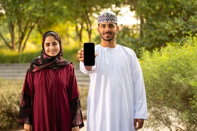 عرض شاشة سوداء عبر الهاتف المحمول ، زوجان عربيان عمانيان يرتديان الزي التقليدي يقومان بالتنزه في الهواء الطلق بإحدى الحدائق، قضاء اوقات عائلية ممتعة، منظر العشب والأشجار الخضراء في وضح النهار عرض شاشة سوداء عبر الهاتف المحمول ، زوجان عربيان عمانيان يرتديان الزي التقليدي يقومان بالتنزه في الهواء الطلق بإحدى الحدائق، قضاء اوقات عائلية ممتعة، منظر العشب والأشجار الخضراء في وضح النهار