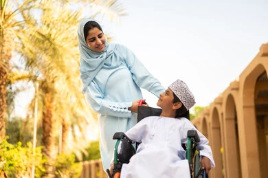 أجواء عائلية مرحة ، عائلة عربية عمانية خليجية في رحلة بإحدى الحدائق في سلطنه عمان ، مفهوم الأسرة السعيدة ، قضاء أوقات عائلية ممتعة ، عطلة نهاية الأسبوع ،ولد عربي خليجي عماني يرتدي الدشداشة و الكمه يجلس على كرسي متحرك يقوم بالنظر الى والدته بايماءات الحب و السعادة أجواء عائلية مرحة ، عائلة عربية عمانية خليجية في رحلة بإحدى الحدائق في سلطنه عمان ، مفهوم الأسرة السعيدة ، قضاء أوقات عائلية ممتعة ، عطلة نهاية الأسبوع ،ولد عربي خليجي عماني يرتدي الدشداشة و الكمه يجلس على كرسي متحرك يقوم بالنظر الى والدته بايماءات الحب و السعادة