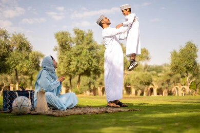 The concept of fatherhood and a father's affection, an Arab Gulf Omani family dressed in traditional attire enjoying the outdoors, an Arab Gulf Omani man wearing a dishdasha and kumma lifting his son up high, gestures of happiness and joy. The concept of fatherhood and a father's affection, an Arab Gulf Omani family dressed in traditional attire enjoying the outdoors, an Arab Gulf Omani man wearing a dishdasha and kumma lifting his son up high, gestures of happiness and joy.