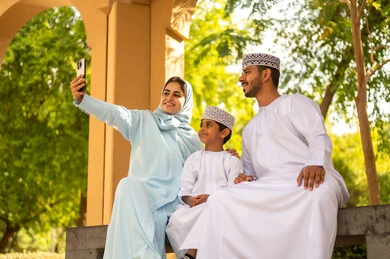 Taking selfies for memories and friendly family gatherings via mobile, an Arab Gulf Omani family wearing traditional attire in one of the parks and outdoor recreational areas, enjoying the outdoors, spending enjoyable times with the children, taking care of and paying attention to the kids, summer recreational activities. Taking selfies for memories and friendly family gatherings via mobile, an Arab Gulf Omani family wearing traditional attire in one of the parks and outdoor recreational areas, enjoying the outdoors, spending enjoyable times with the children, taking care of and paying attention to the kids, summer recreational activities.