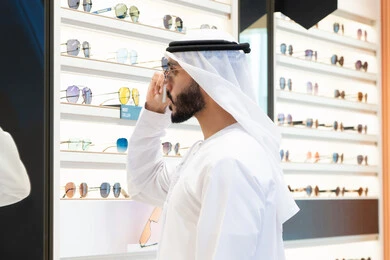 الاهتمام بالمظهر الخارجي، أحدث المنتجات العصرية الحديثة, رجل اماراتي يرتدي الكندوره والغتره البيضاء يقوم بشراء النظارة المناسبة في محل اماراتي،تسوق وشراء  متابعة آخر صيحات الموضة والجمال,الركن الخاص بالنظارات الشمسيه الفخمه